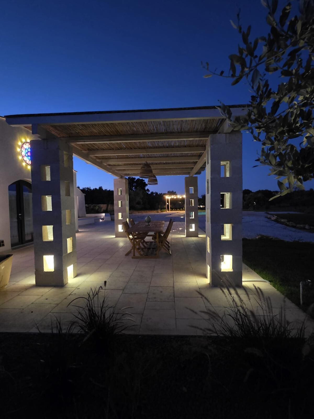 An outdoor patio area with a pergola, a dining table, and chairs.
