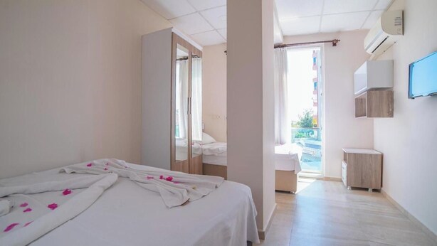 Een hotelkamer met een bed, een spiegel, een kledingkast, een klein tafeltje en een televisie.