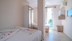 Habitación de hotel con cama, espejo, armario, una mesita y televisión.
