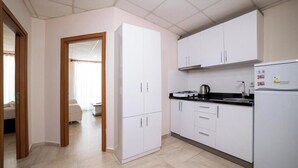 Een moderne keuken met witte kasten, een zwart aanrecht en een koelkast.