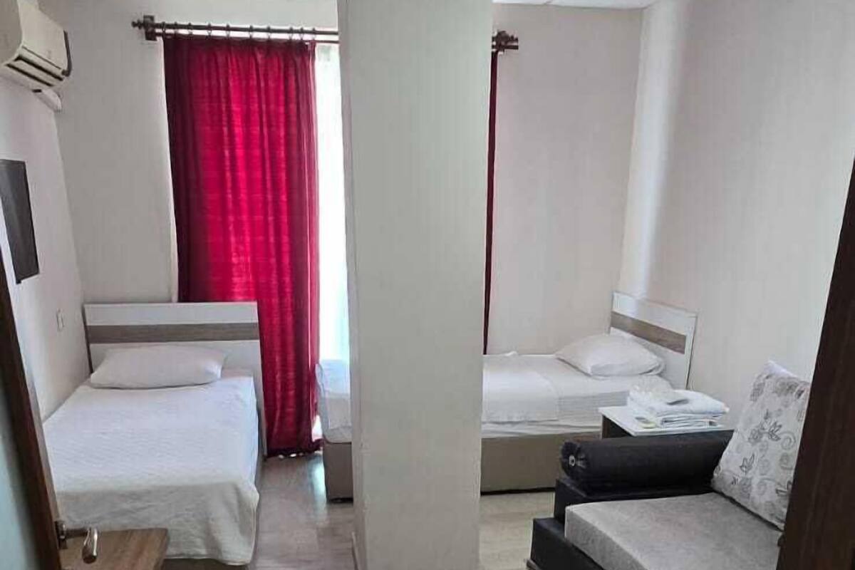 A hotel room with two beds, a sofa, and a small table.
