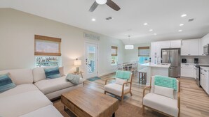 A spacious living room with a sofa, chairs, a coffee table, and a ceiling fan.
