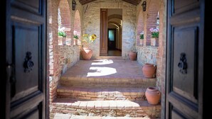 A stone pathway leading to a door with potted plants and a brick wall. - Agriturismo Le Case (Castiglione d'Orcia)