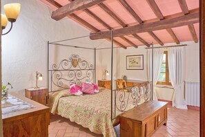A bedroom with a four-poster bed, wooden furniture, a window with curtains, and a radiator. - Agriturismo Le Case (Castiglione d'Orcia)