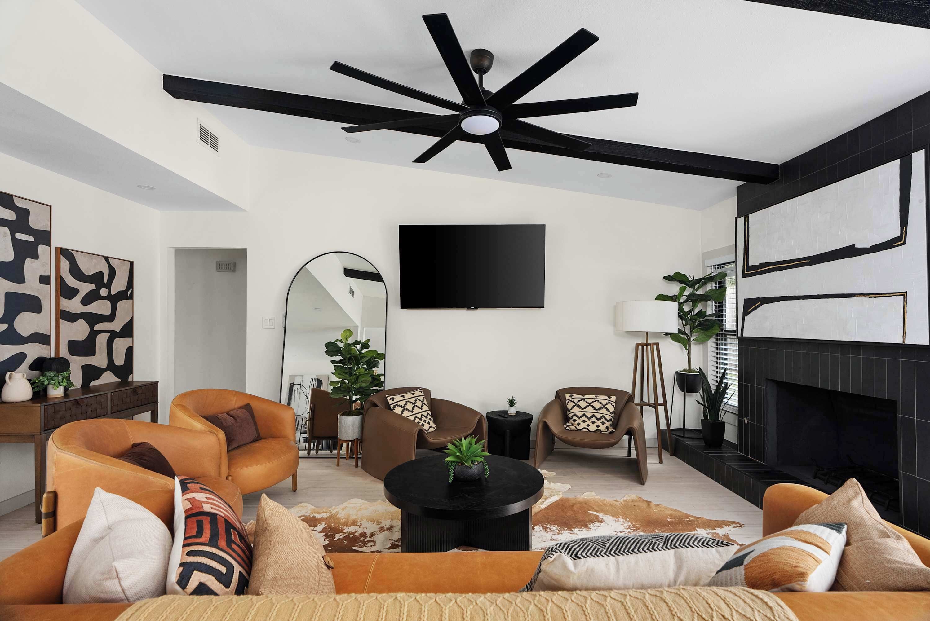 A modern living room with a ceiling fan, a flat-screen TV, and a fireplace.