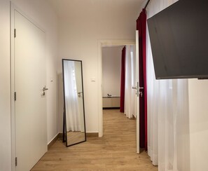 A hallway with wooden flooring, white walls, and a mirror on the left. - Pet'inn I, Pet'inn I by Ruby Red House (Sofia)