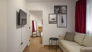 A modern living room with a sofa, a TV mounted on the wall, a small side table, and a mirror. - Pet'inn II, Pet'inn II by Ruby Red House (Sofia)
