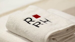 A folded white towel with embroidered text and a red square. - Pet'inn II, Pet'inn II by Ruby Red House (Sofia)