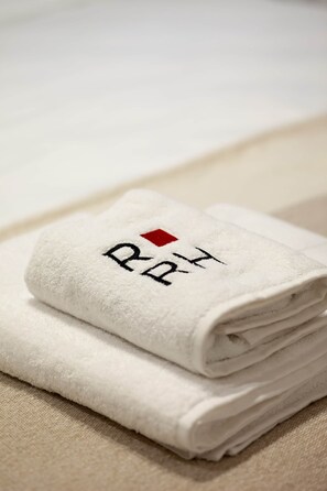 A folded white towel with embroidered text and a red square.