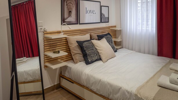 A bedroom with a bed, bedside tables, a mirror, and artwork on the wall. - Pet'inn II, Pet'inn II by Ruby Red House (Sofia)