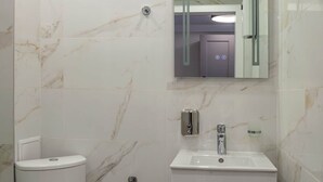 Ein Badezimmer mit Toilette, Waschbecken, Spiegel und Marmorfliesen.