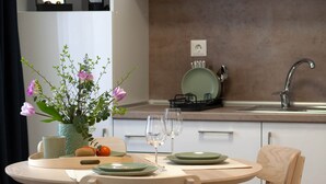 Une cuisine moderne avec des meubles blancs, une table de salle à manger ronde et un vase rempli de fleurs.