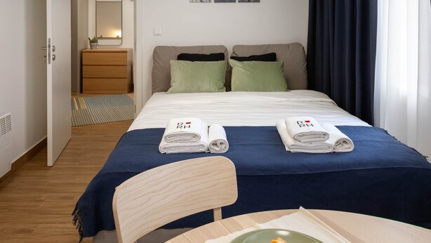 Une chambre d’hôtel avec un lit, une table sur laquelle se trouve une assiette de fruits, un miroir et des œuvres d’art accrochées au mur.