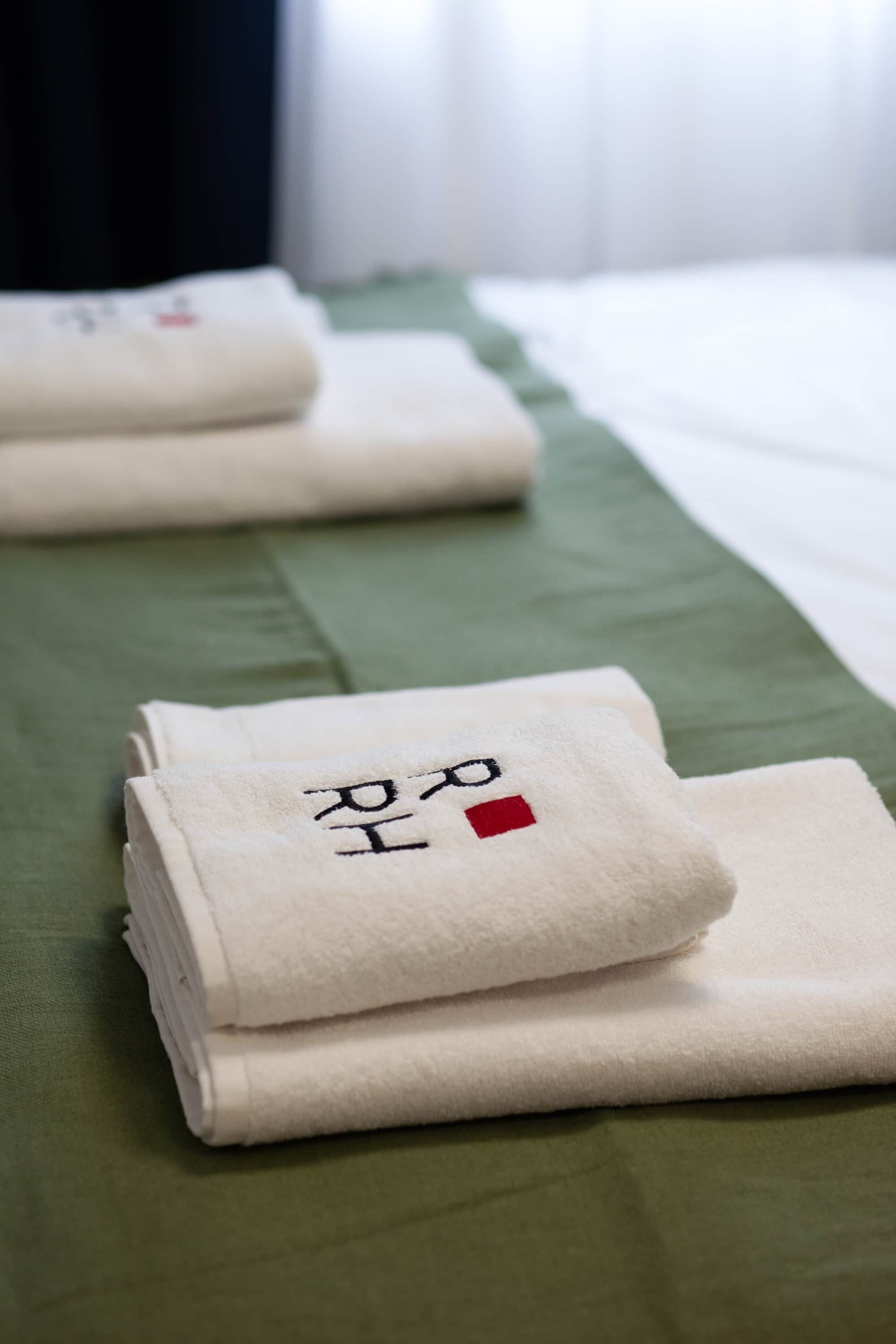 Neatly folded towels with Korean characters on a bed with a green bedspread.