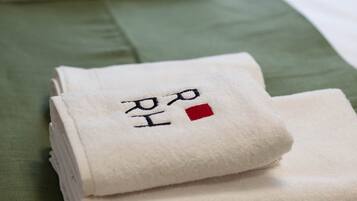Neatly folded towels with Korean characters on a bed with a green bedspread.