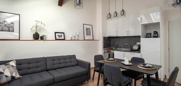 Une cuisine moderne avec des meubles blancs, une table à manger et un canapé.