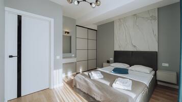 A modern bedroom with a large bed, built-in wardrobe, and a marble accent wall.
