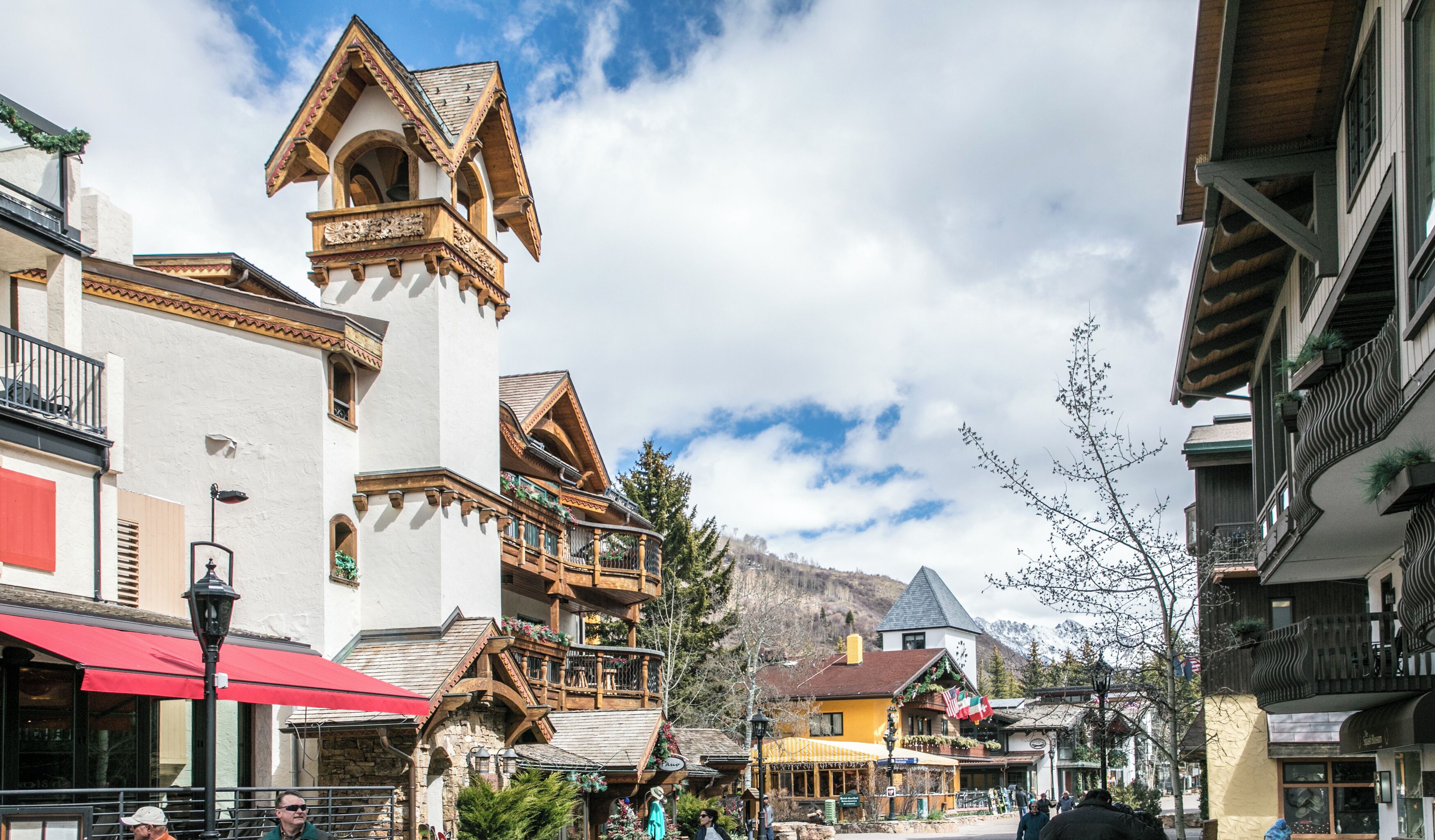 Un edificio de estilo europeo tradicional con una torre destacada, fachada de piedra y balcones de madera.