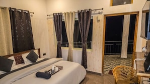 Una camera d'albergo con un letto, un tavolino con un bollitore, una sedia e un balcone con pavimento a scacchi.
