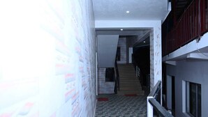 Un corridoio con pavimento decorato, una scala e un muro con motivo floreale.