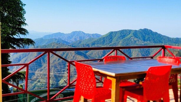 Una terrazza con tavolo e sedie, vista su un paesaggio montuoso.