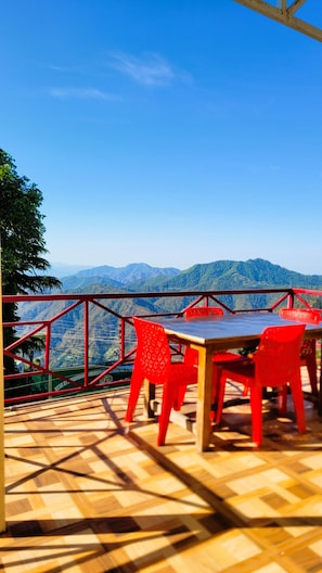 A terrace with a table and chairs, overlooking a mountainous landscape. - Morning Breeze Homestay Kanatal (Tehri Range)