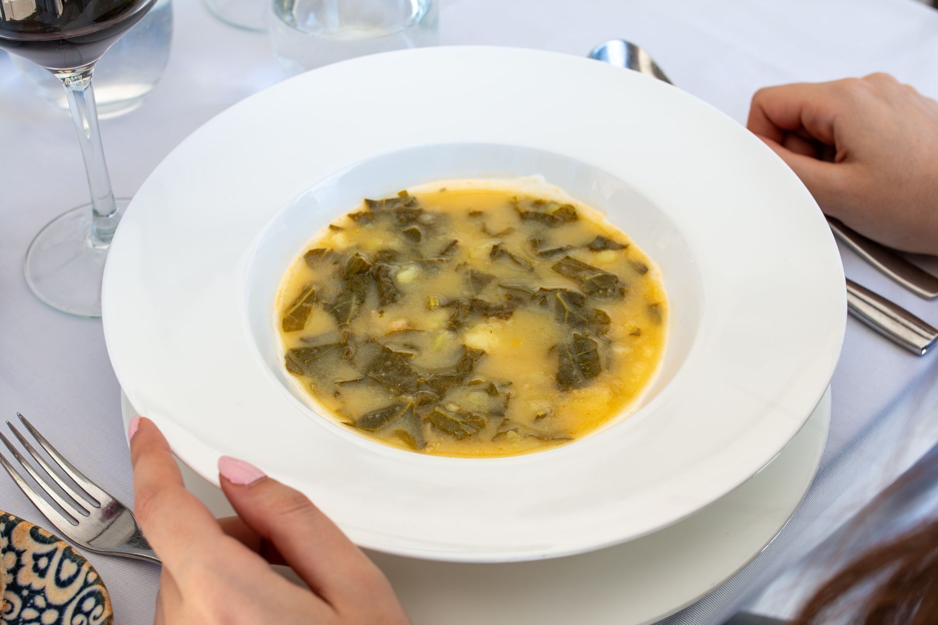 Eine weiße Schüssel Suppe mit Gabel und Löffel auf einem Tisch.