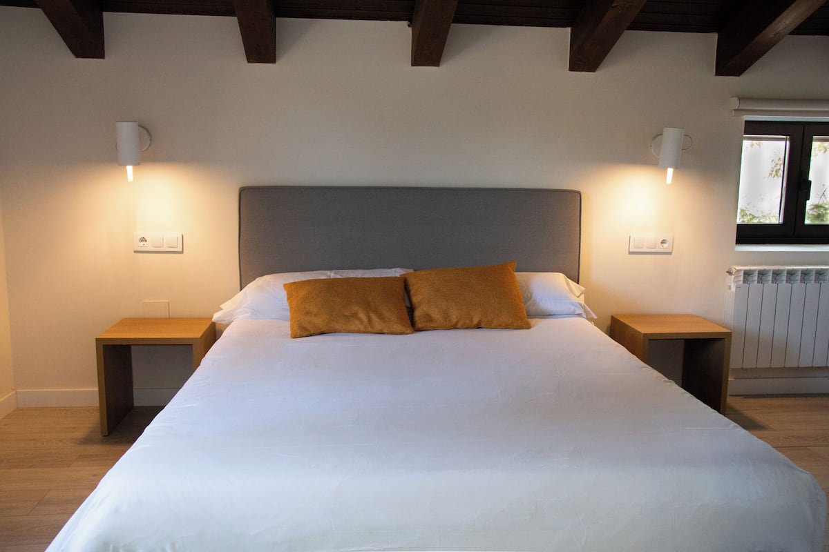 Ein Schlafzimmer mit einem großen Bett, zwei Nachttischen und Wandleuchten.