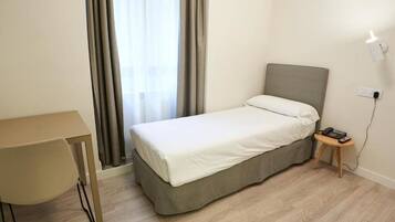 Una habitación pequeña y ordenada con una cama, un escritorio y una silla.