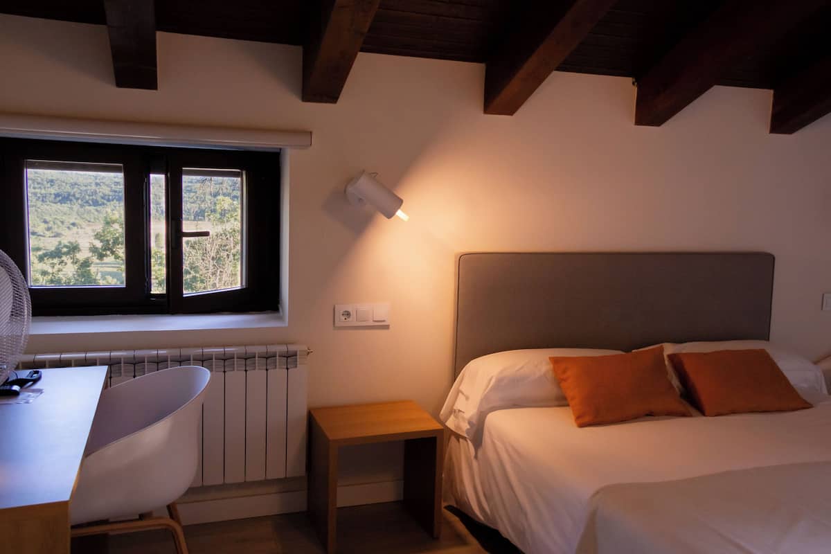 Ein Schlafzimmer mit Bett, Nachttisch, Stuhl, Fenster und Heizkörper.