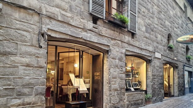 A stone building with a restaurant entrance featuring a menu board and outdoor seating. - LocandaMimmo (Bergamo)