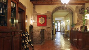 A spacious hallway with a stone fireplace, wooden cabinets, and a wine rack. - LocandaMimmo (Bergamo)