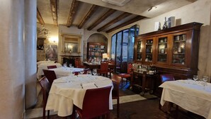 A restaurant with multiple tables set for dining, a bar area with bottles, and a fireplace. - LocandaMimmo (Bergamo)