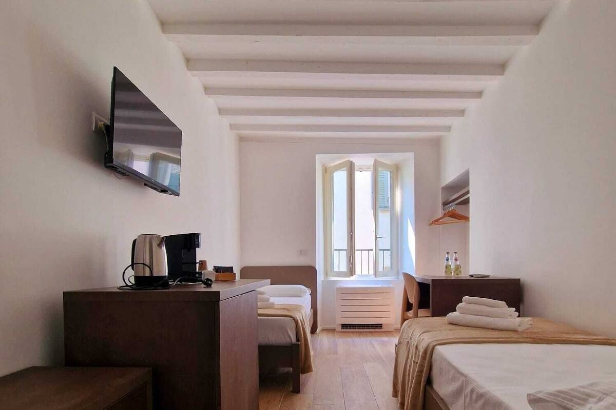 Une chambre d’hôtel avec un bureau en bois, un lit, un téléviseur fixé au mur et une fenêtre donnant sur l’extérieur.
