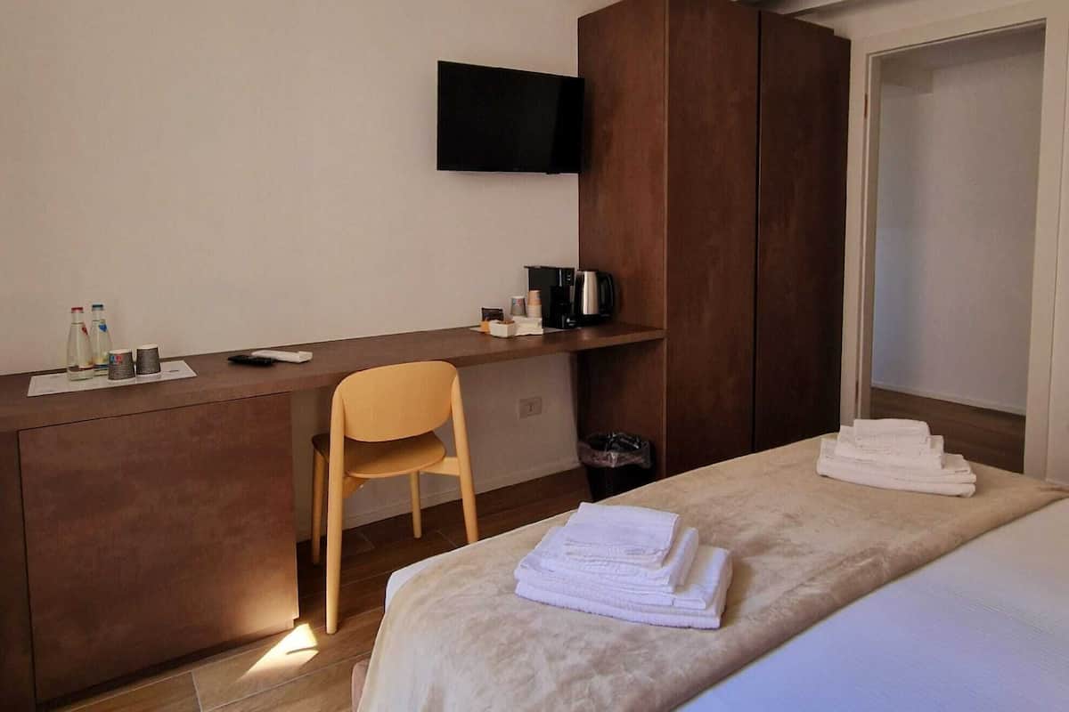 Une chambre d’hôtel équipée d’un lit, d’un bureau, d’une chaise, d’un téléviseur fixé au mur et d’une armoire.