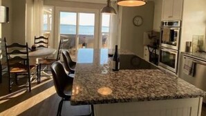 A kitchen with a central island, pendant lighting, and a view to the outside.