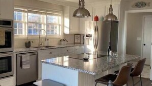 A modern kitchen with a central island, stainless steel appliances, and pendant lighting.