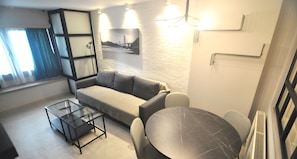 Appartamento Superior, vista città | Area soggiorno | TV a schermo piatto 50 pollici con canali digitali, film pay-per-view