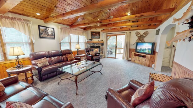 A cozy living room with leather sofas, a glass coffee table, and a fireplace. - Sycamore Cabin with Hot Tub Breathtaking Views (Gaines)
