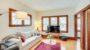 A modern living room with a sofa, coffee table, TV, and large windows. - Walk to Shops & Eats: Home w/ Deck in Minneapolis (Minneapolis)