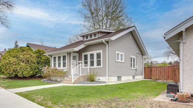 A two-story house with a front porch, a small front yard, and a wooden fence in the background. - Walk to Shops & Eats: Home w/ Deck in Minneapolis (Minneapolis)