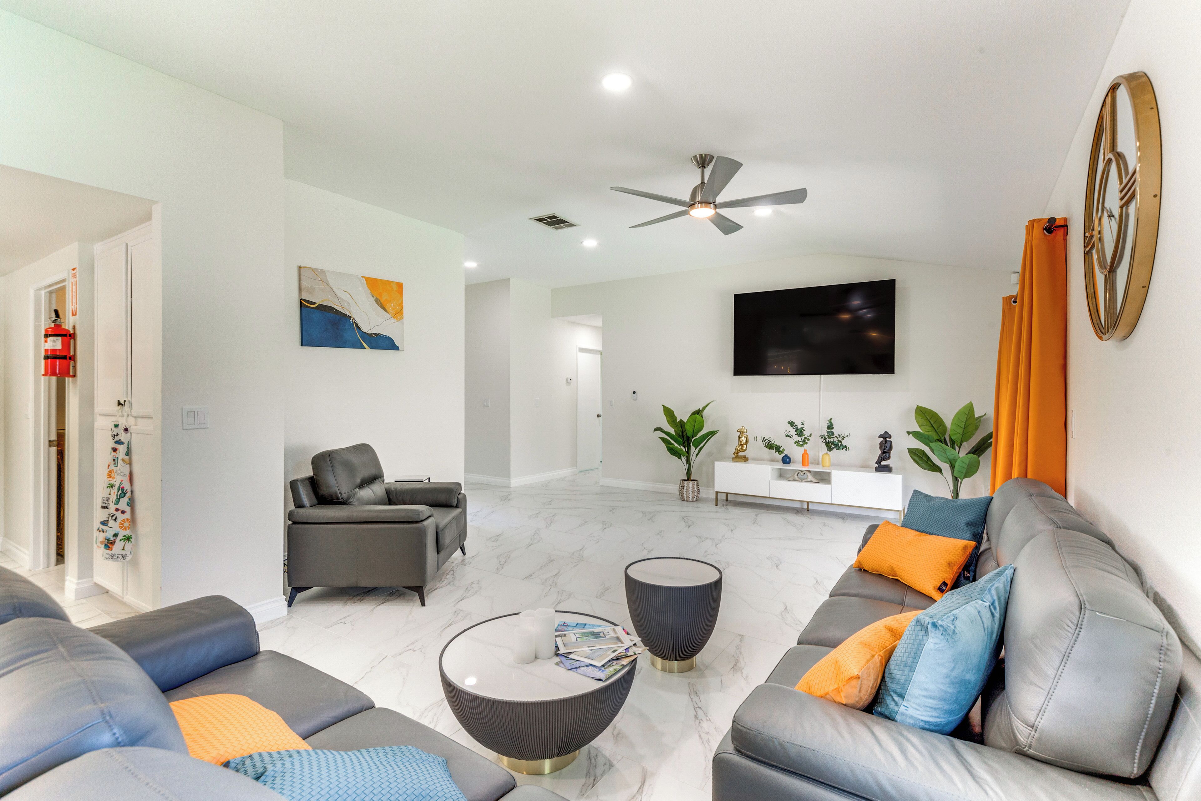 A modern living room with a grey sofa set, a round coffee table, and a ceiling fan.