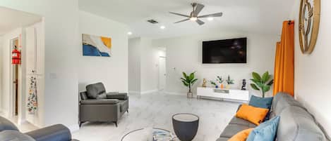 A modern living room with a grey sofa set, a round coffee table, and a ceiling fan.