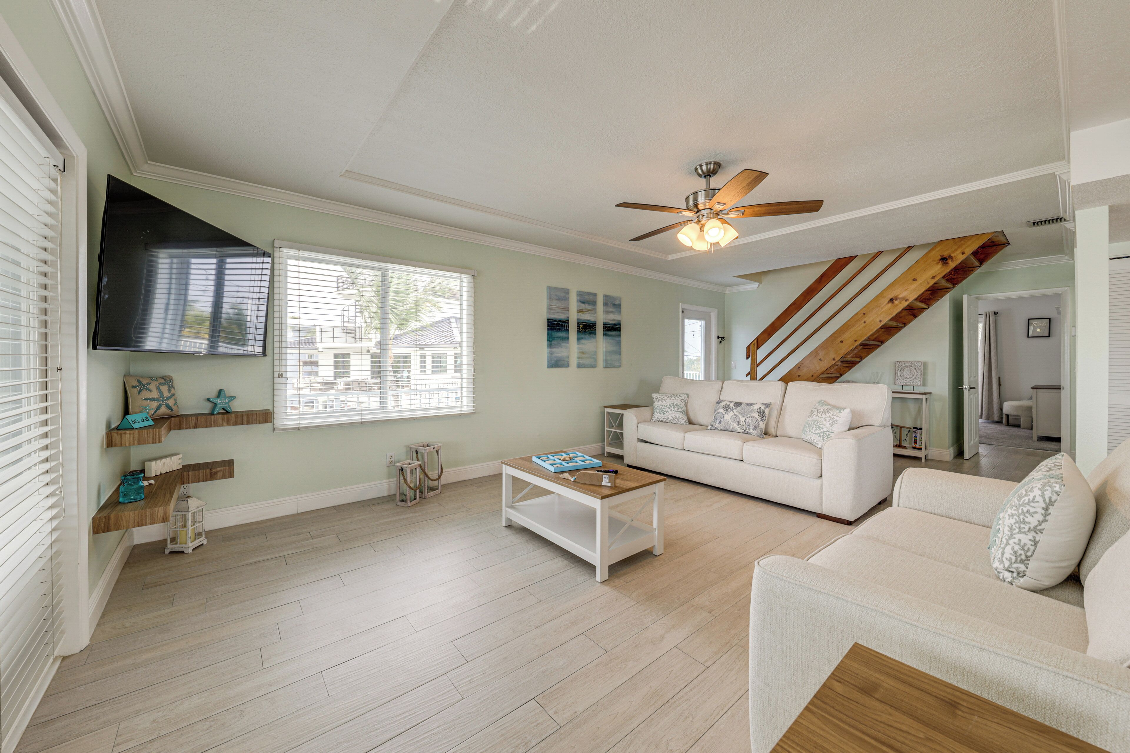 A spacious living room with a white sofa, a coffee table, and a ceiling fan.