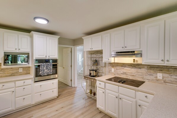 A modern kitchen with white cabinetry, a stainless steel oven, a built-in microwave, and a stone backsplash. - Waterfront Home w/ Fishing Dock in Tallahassee! (Tallahassee)