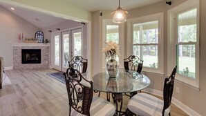 A dining area with a glass table, striped chairs, a vase with flowers, and a fireplace. - Waterfront Home w/ Fishing Dock in Tallahassee! (Tallahassee)