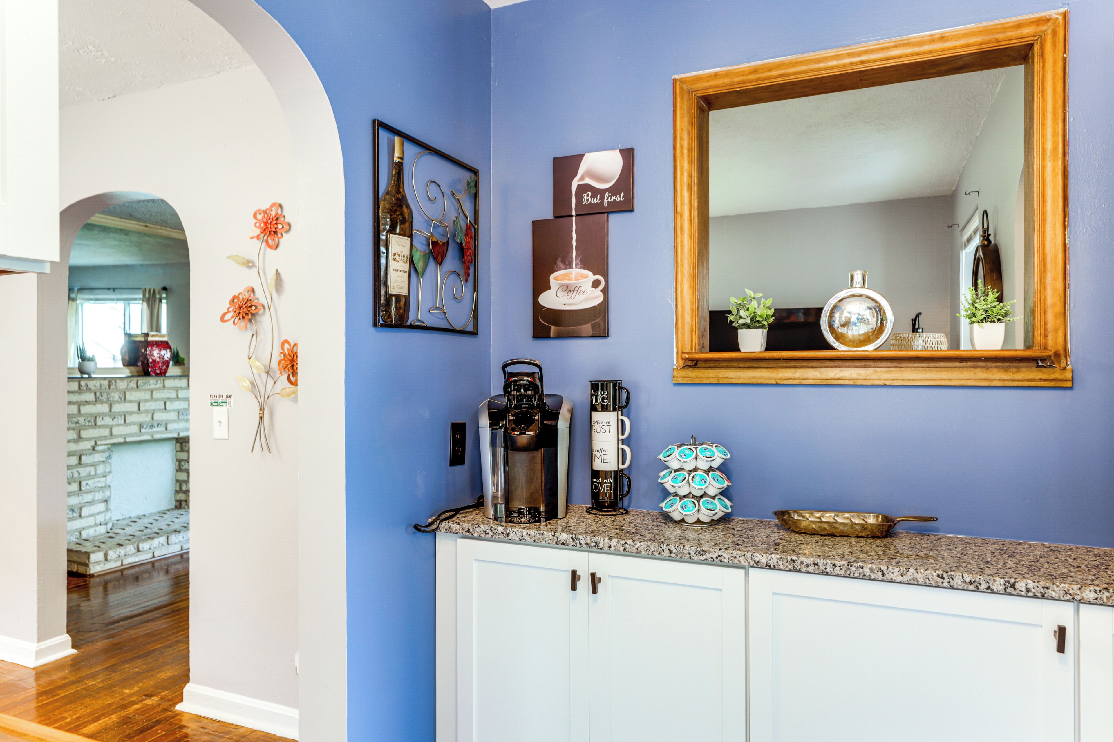 A kitchen with a blue wall, a coffee maker, a coffee mug, and a decorative plate.