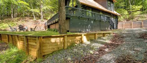 A cabin with a wooden deck, a covered porch, and a staircase leading to the upper level.