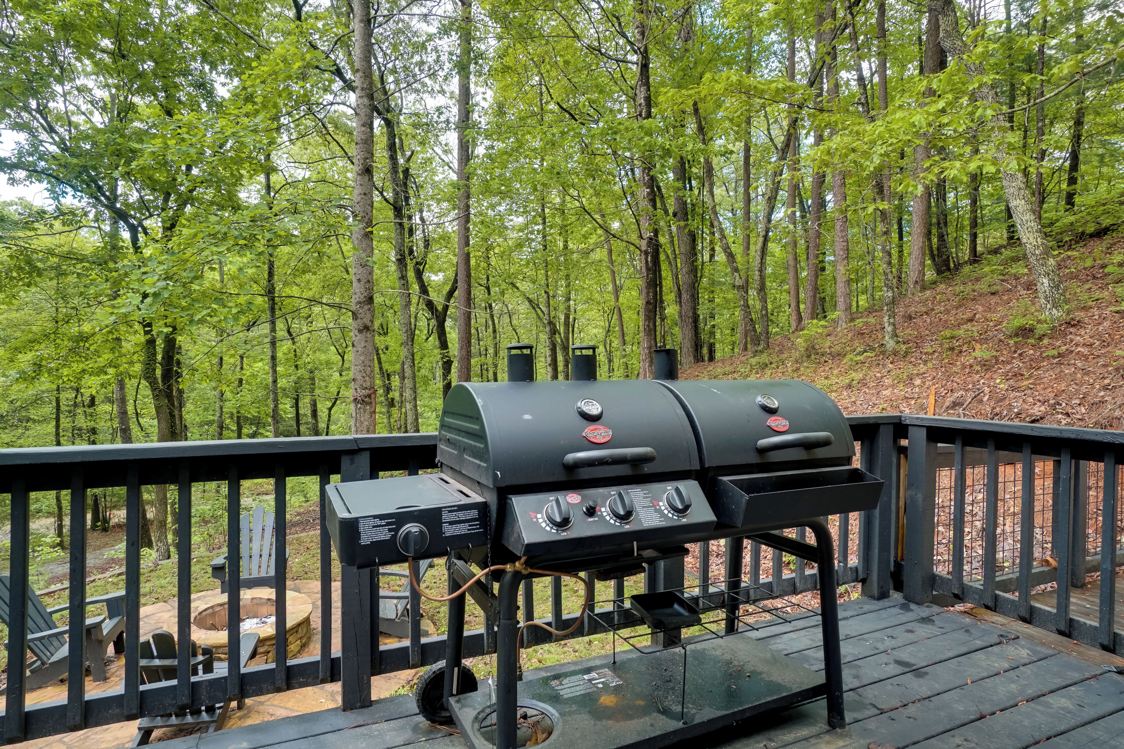 A barbecue grill on a wooden deck with a view of a forest.