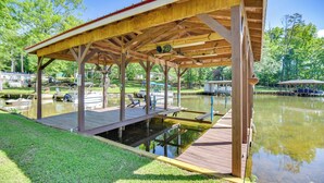 A wooden dock with a covered pavilion over a pond, surrounded by greenery and boats. - Private Dock: Pet-friendly Home on Lake Sinclair (Milledgeville)